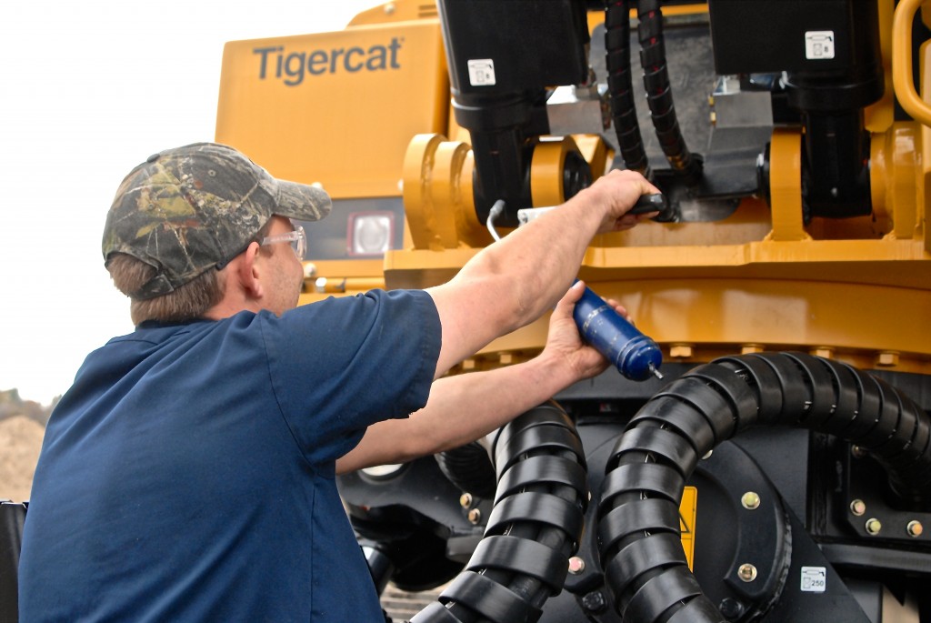 En förare som utför regelbunden smörjning av en Tigercat-maskin.