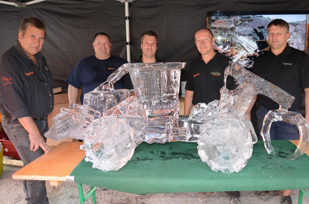 Dieter Clohse, Marc Breuer, Piers Eyre-Walker et Eddie Leboutte de Clohse Group, ainsi que le client de Tigercat et champion de sculpture à la scie à chaîne Nicolas Gombert (au centre), posent pour une photo à côté d'une sculpture en glace d'un débardeur 610E créée par M. Gombert pour l'événement.