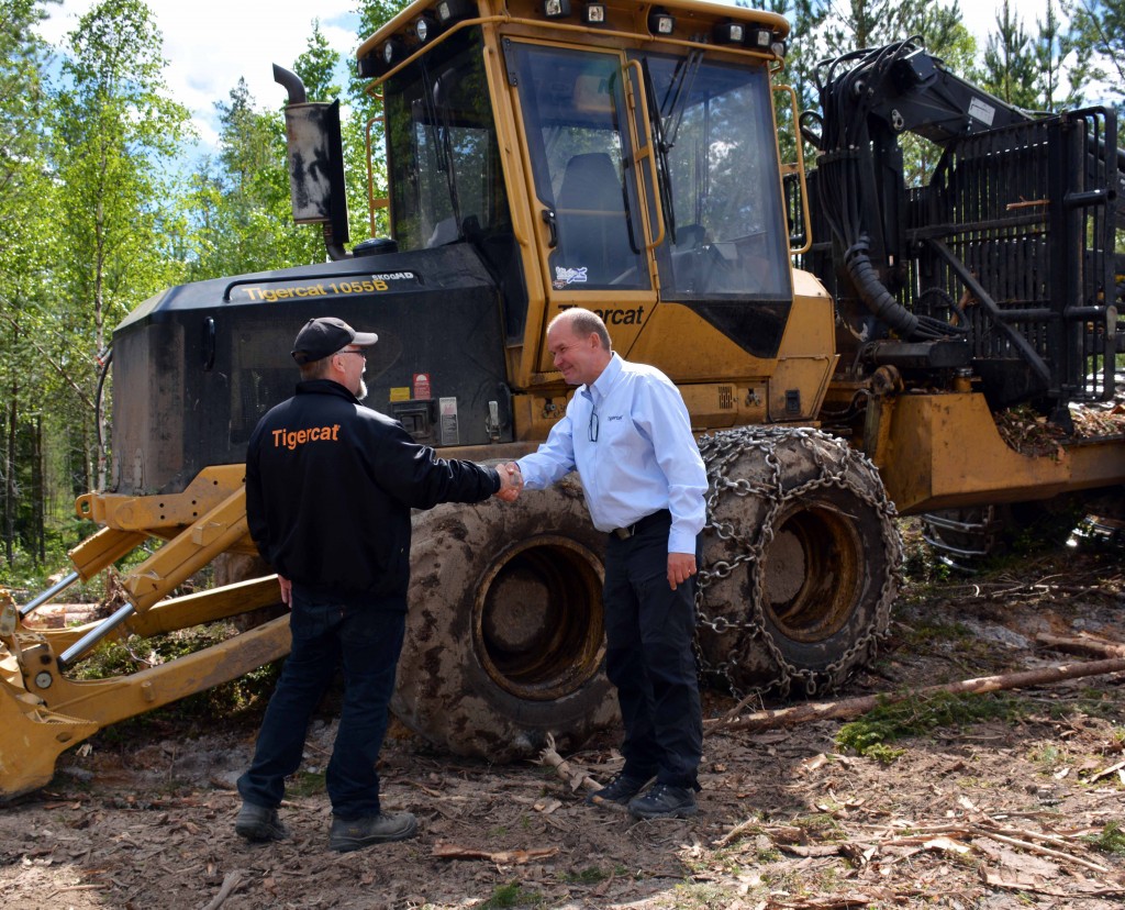 Mats Danielsson, propriétaire de MD Skog, et Sven-Ake Stenberg, directeur régional de Tigercat, se serrent la main devant un transporteur forestier 1055B.