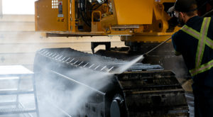 Picture of a guy cleaning tracks of a Tigercat machine