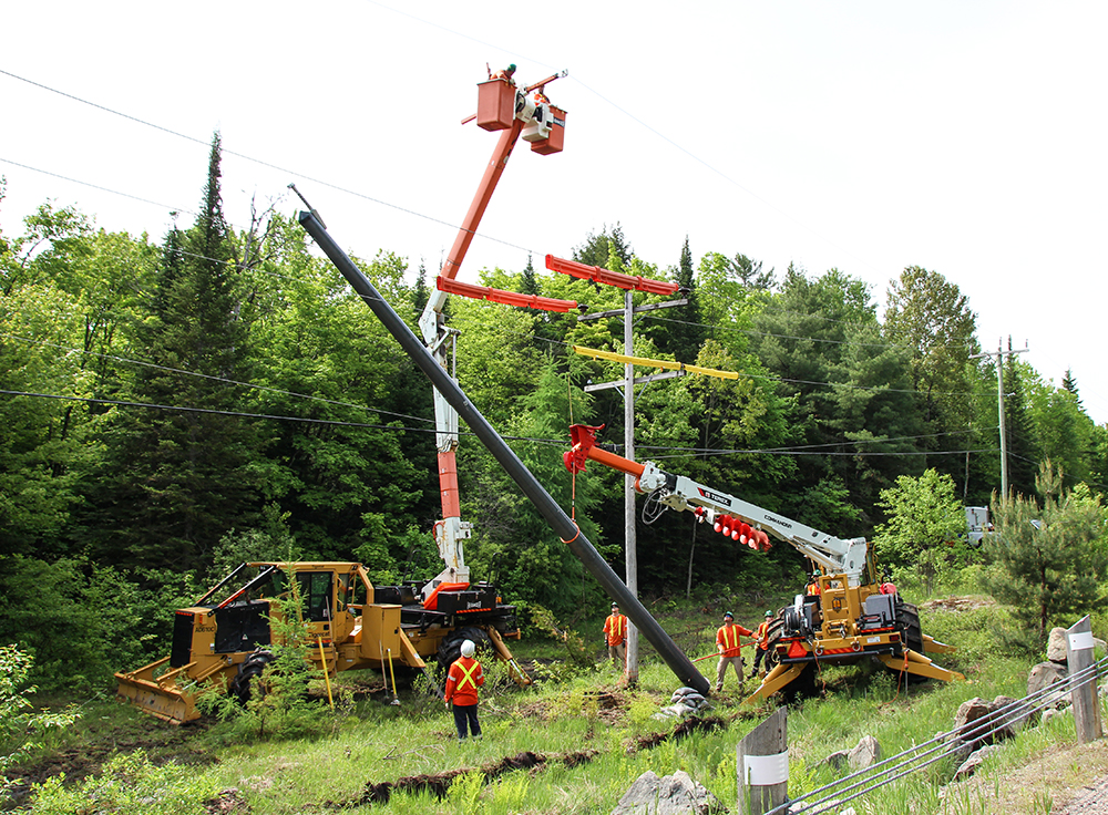 Two AD610C utility carriers work in tandem on a hydro pole replacement operation.