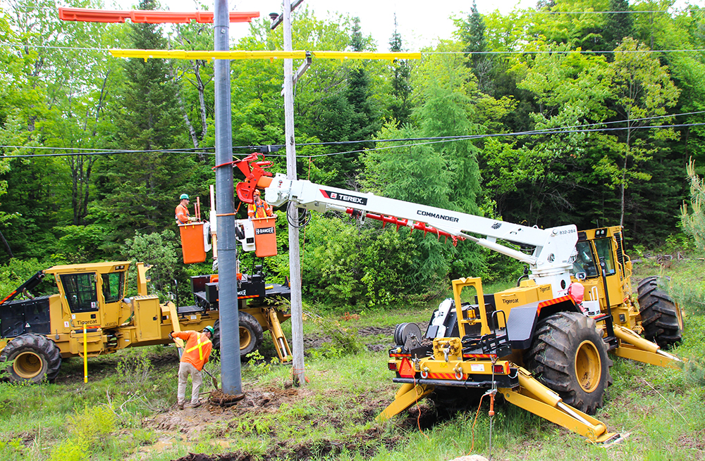 Un AD610C équipé d'une tarière tient le nouveau poteau en place.