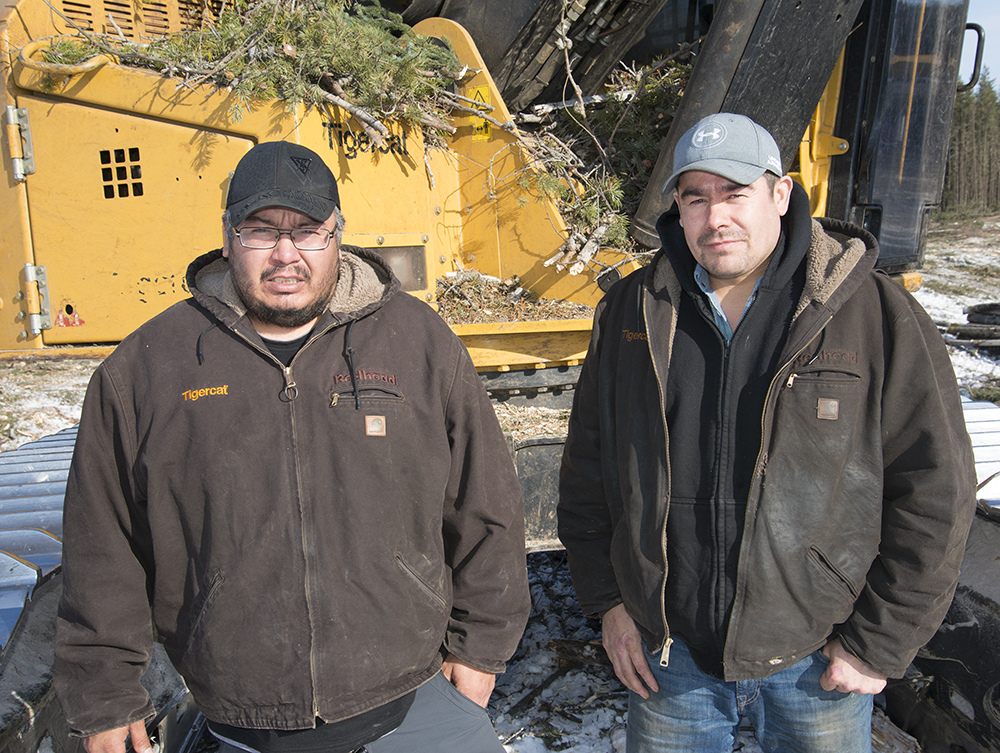 Les frères Darren et Gary Thomas de Thomas Logging Ltd. devant une de leurs machines Tigercat