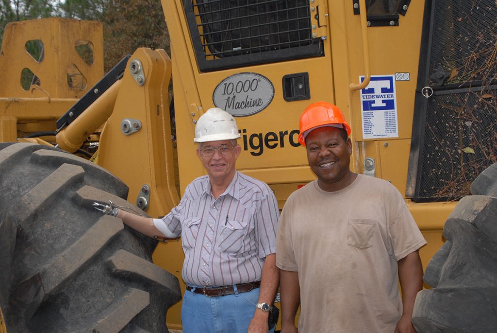 Robert stands laughing with Russell Brown (Hollywood), the operator of the 10,000th machine, which is also the 50th Tigercat for Clary Logging.