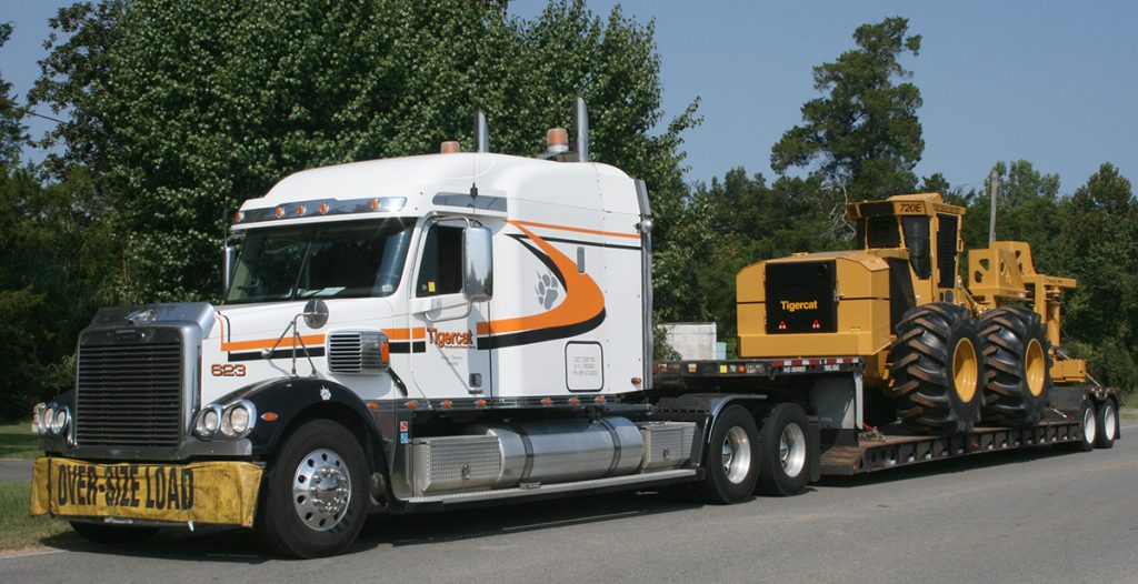 The 10,000th machine being delivered by a Tigercat transport truck.