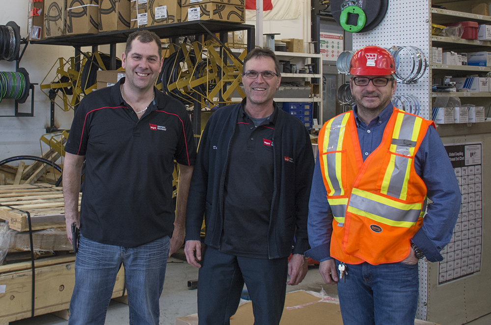 3 men standing smiling in wajax polos and saftey gear.