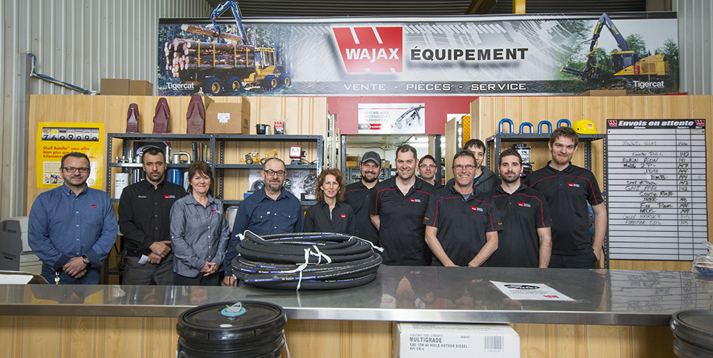 Le personnel de bureau dévoué de la succursale de Wajax à Saint-Félicien, posant derrière un comptoir de pièces de rechange (G-D) : Sylvain, Dominic, Ghislaine, Gilles, Chantale, Bruno, Pierre, Frederic, Denis, Matthieu, Eric, Jonathan.