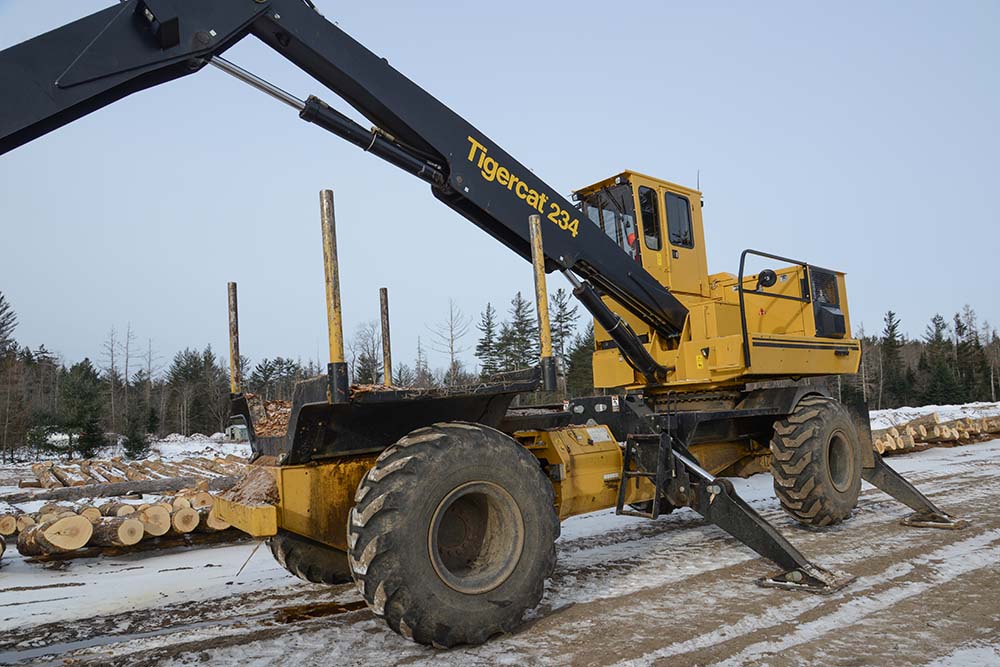 A Tigercat 234 mounted on an AC16 articulating carrier unloads the logs and spreads them out on stringers.