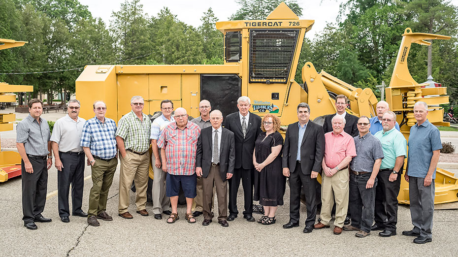 Un groupe d'employés de Tigercat posent devant la première machine Tigercat jamais fabriquée