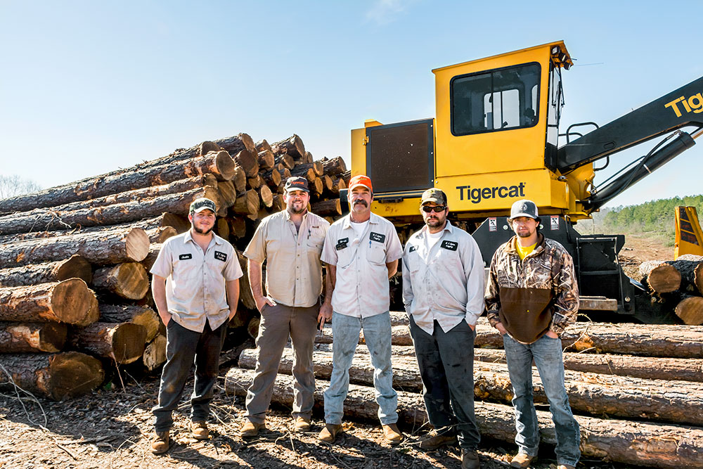 The clear fell crew stand in front of a Tigercat loader. 