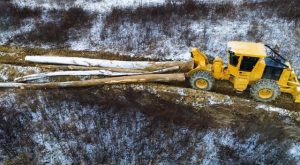 Aerial view of a 602 Winch Skidder in the winter pulling a large load of hard wood