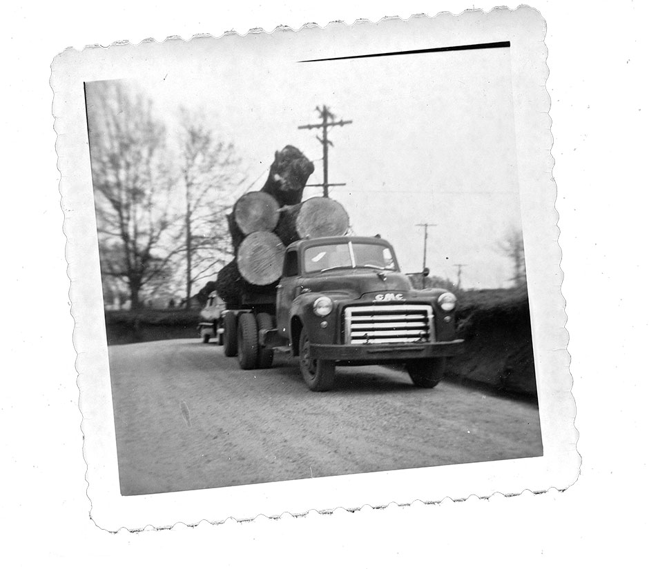 A black and white image of a 1950's GMC truck hauling logs.