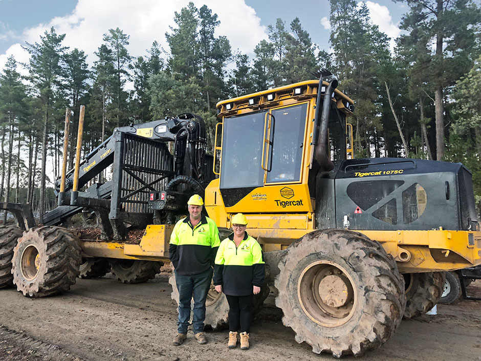 Peter and Theresa Lonergan standing in front of a Tigercat 1085C Forwarder