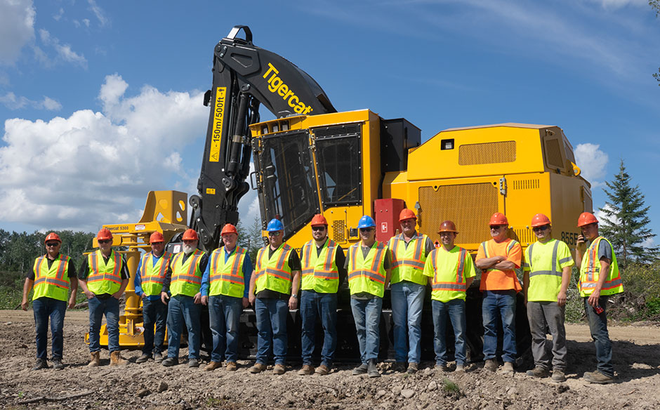 A group of vistors stand in front of a Tigercat machine.