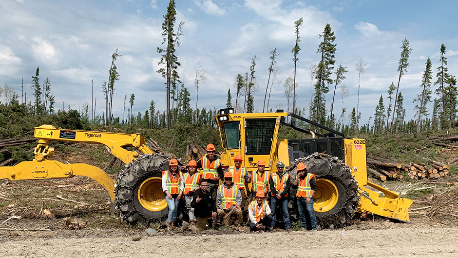 A group of logging trainees in front of a Tigercat skidder.