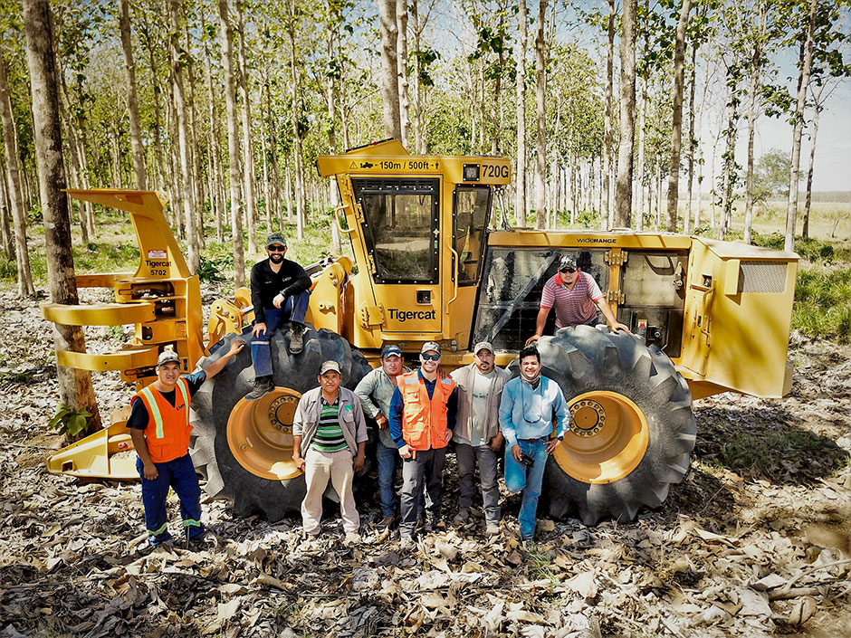 Latin Equipment Norte staff and the harvesting team in front go the 718G feller buncher.