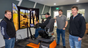 Andy Driedger, owner of Garden River Logging Ltd. (seated) takes the processor simulator through its paces. Philip Unrau, CEO of FTEN Group of Companies at left, along with Gregor Scott from the Tigercat electronic systems group, and forestry consultant, Jon Goertzen at right.