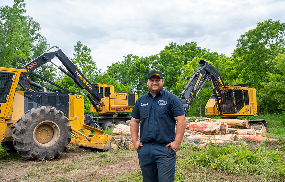 Colton Fodor standing in front of Tigercat machines